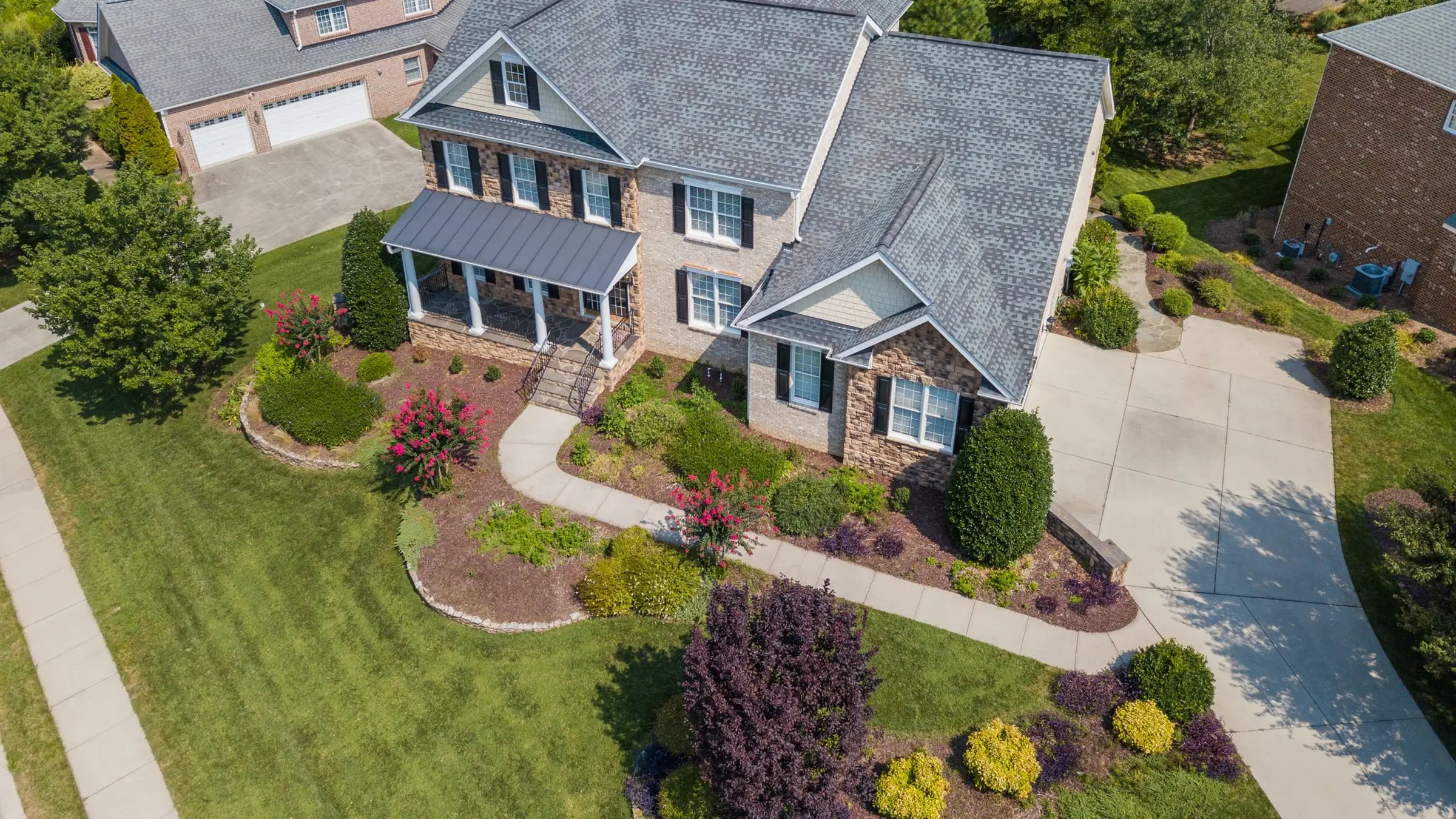 Aerial view of a two-story brick house, curved walks, and green lawns